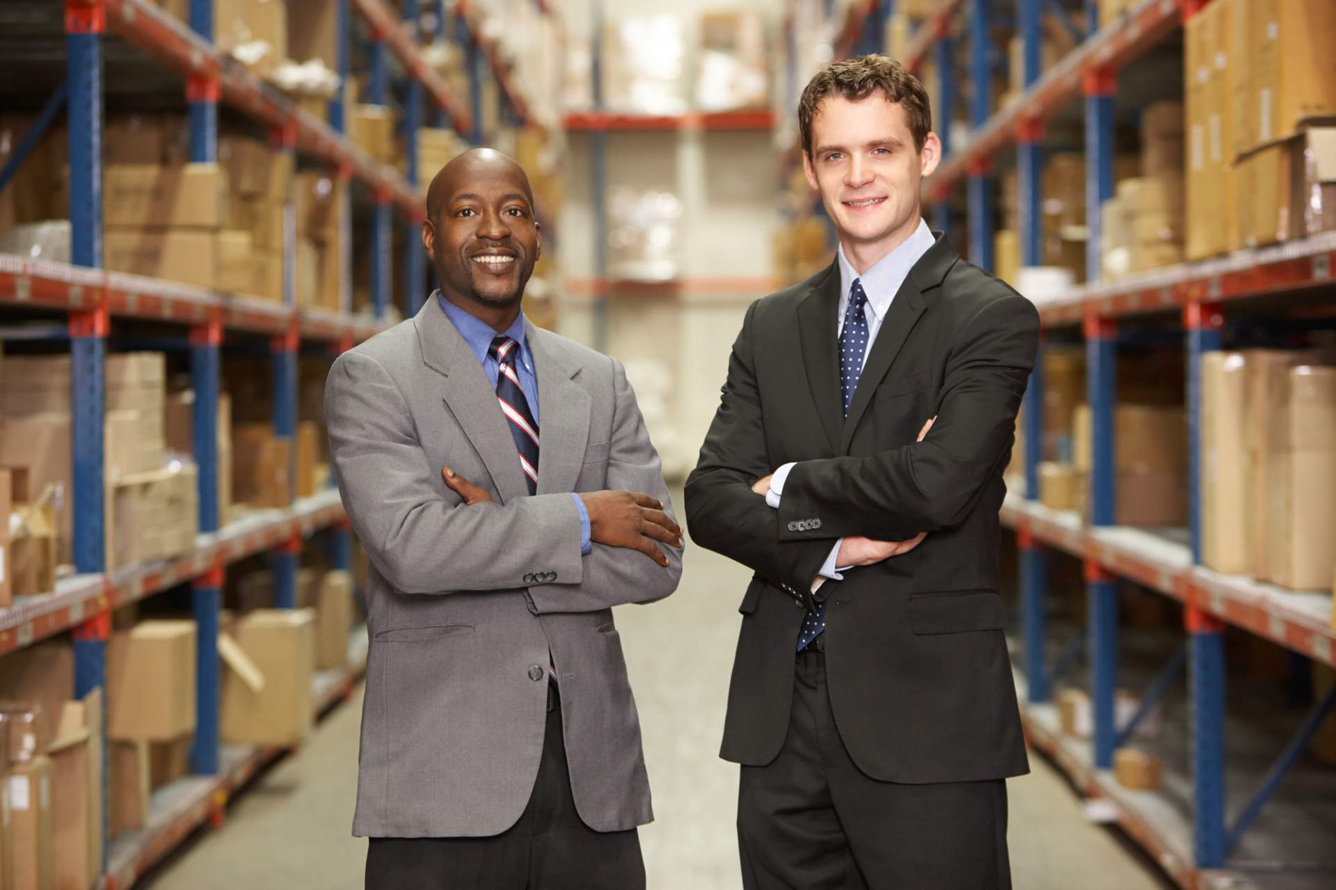 Young African American and White man with arms folded in a warehouse